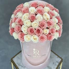 Pink and white roses arranged in a round hatbox.