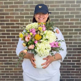 Person holding a colorful flower arrangement in a white vase