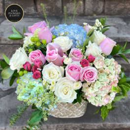 Pastel pink and white roses with hydrangeas arranged in a patterned ceramic vase