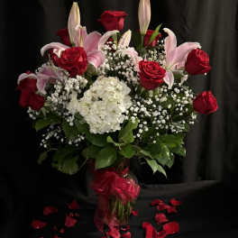 Bouquet of red roses and pink lilies with white hydrangea in a glass vase
