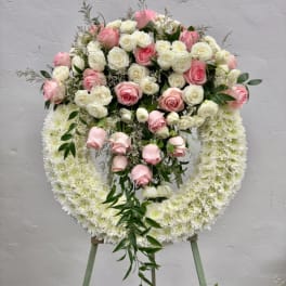 Pink and white rose funeral wreath on an easel