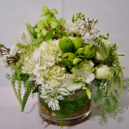 White and green floral arrangement in a glass vase with lime accents
