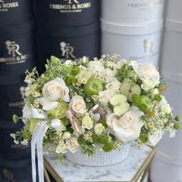 White and green floral arrangement with apples in a white hatbox