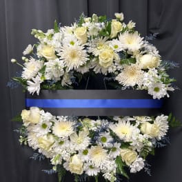 White floral funeral wreath with roses and daisies on a black stand