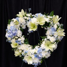 Heart-shaped floral wreath with white and pale blue flowers on a stand