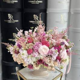 Pink and cream rose arrangement in a pedestal vase with ribbon