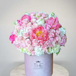 Pink and white flower arrangement in a lavender hat box