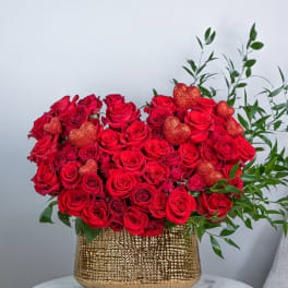 Red roses with glittery heart accents in a gold vase