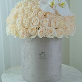 Cream rose bouquet in a gray hat box with white orchids