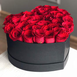 Round box of red roses in a black container