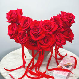 Heart-shaped bouquet of red roses with ribbon and a chocolate box