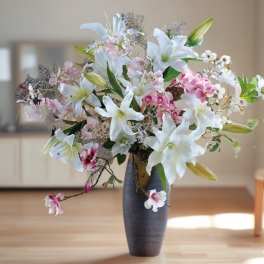 White lilies and pink orchids in a tall dark vase