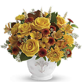 Yellow roses and autumn flowers arranged in a white vase