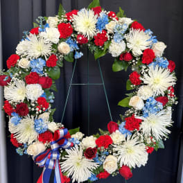 Large patriotic floral wreath with red, white, and blue flowers on a stand