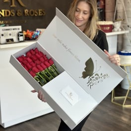 Box of red roses held open by a woman