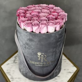 Pink roses arranged in a gray round hat box