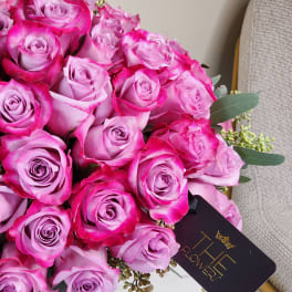Bouquet of pink roses in a glass vase with a black tag