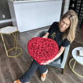 Woman holding a large heart-shaped bouquet of red roses