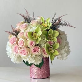 Pink roses and green orchids in a glittery pink vase