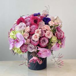 Pink and purple roses with orchids in a dark vase