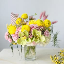 Pink and yellow flower bouquet in a clear glass vase