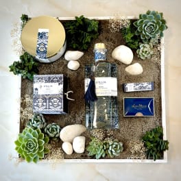 Gift box arrangement with candles, perfume, succulents, and white stones