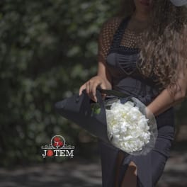 Woman holding a bouquet of white flowers wrapped in black paper