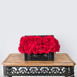 Red roses arranged in a black box on a wooden table