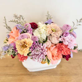Mixed pastel flower arrangement in a white ceramic vase
