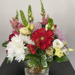Mixed bouquet in a square glass vase with red, white, pink, and yellow blooms
