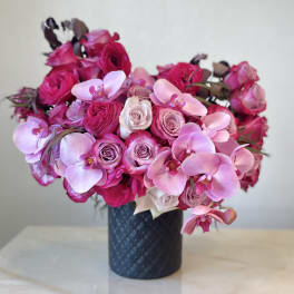 Pink roses and orchids arranged in a dark vase
