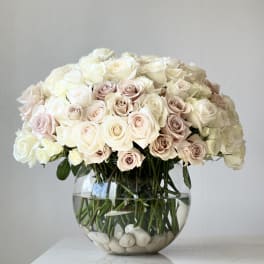 Round bouquet of pale roses in a clear glass bowl vase