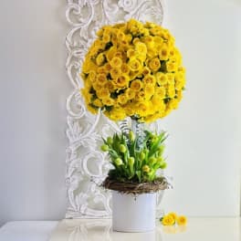 Tall yellow rose arrangement with green buds in a white vase