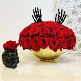 Red rose arrangement in a gold bowl with black decorative accents.