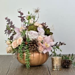 Floral arrangement in a copper pumpkin container with roses and orchids