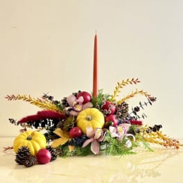 Autumn centerpiece with pumpkins, flowers, and a tall candle