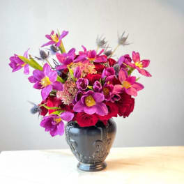 Bright pink and purple bouquet in a dark decorative vase