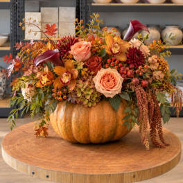 Autumn floral arrangement in a pumpkin container with roses and orchids
