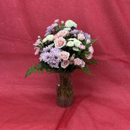 Pink and lavender flowers arranged in a glass vase