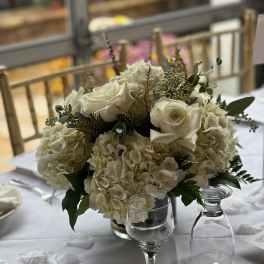 White rose and hydrangea centerpiece in a glass vase