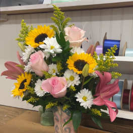 Bouquet in a decorative cowboy boot vase with sunflowers, pink roses, lilies, and daisies