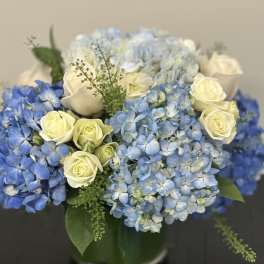 Blue hydrangeas and cream roses in a glass vase