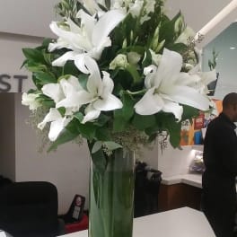 Tall white lily arrangement in a clear glass vase