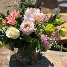 Mixed pastel bouquet in a glass vase with roses and ranunculus