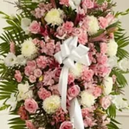 Standing floral spray of pink and white flowers with a white ribbon