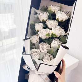 Bouquet of white roses wrapped in black and white paper