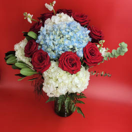 Red roses and blue-white hydrangeas in a dark vase