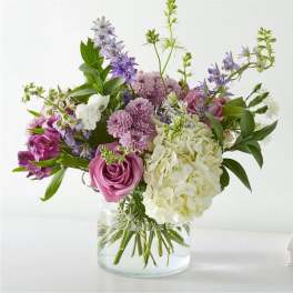 Mixed bouquet of pink, white, and purple flowers in a clear glass vase