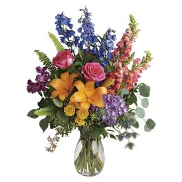 Colorful bouquet of roses, lilies, and snapdragons in a glass vase