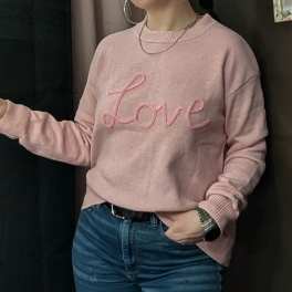 Person wearing a pink sweater with the word "Love" on it